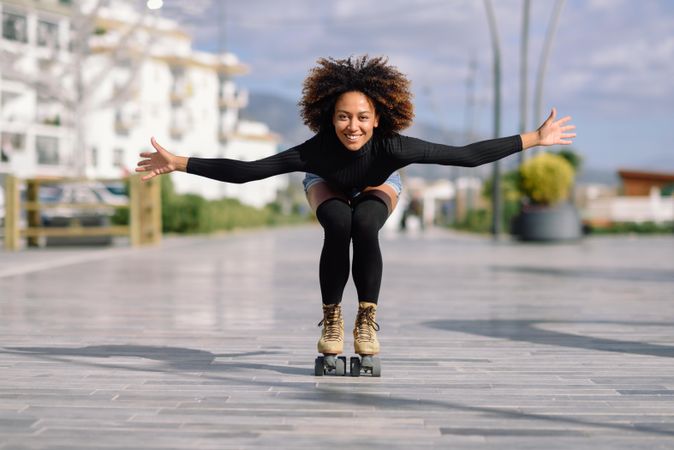 Black female with afro and arms spread roller skating