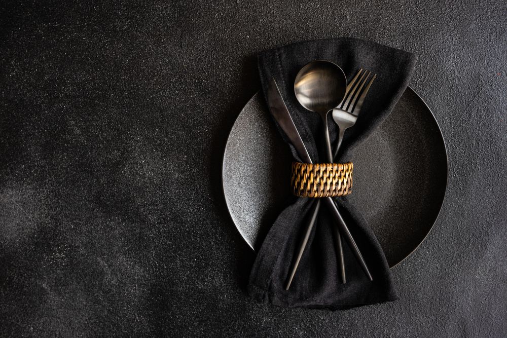 Dark napkin wrapping silverware on plate