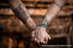 Cropped image of two people with tattooed sleeve holding hands bxKaB4