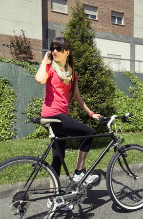 Sportive woman with fixie bike calling by phone