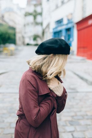 Side view of woman in red jacket and dark hat standing outdoor