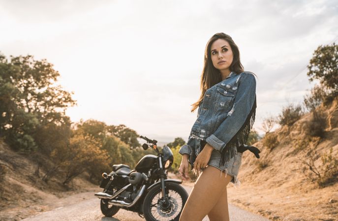 woman with helmet standing beside parked motorcycle