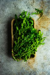 Arugula herb in basket on concrete background