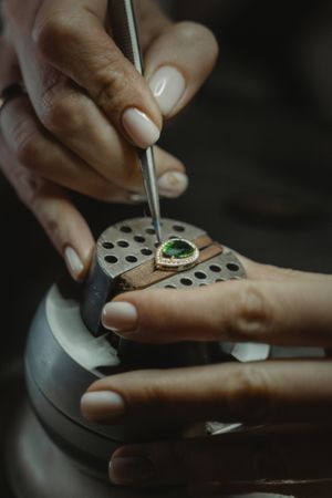 Cropped image of jeweler making a pendant with green gemstone