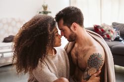 Multiethnic couple hugging on floor at home