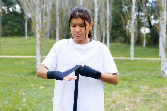 Boxer woman wrapping hands bandage for boxing outdoors