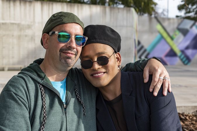 Gay male couple hugging and looking at camera