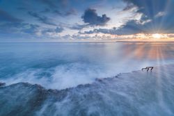 Sun rising over waving sea