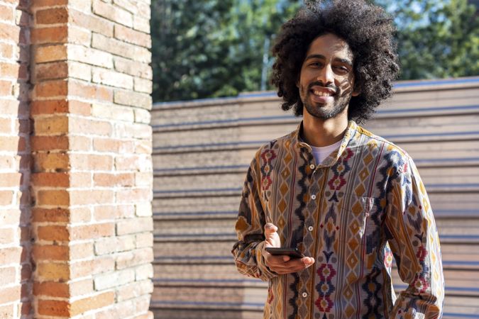 Black man using a mobile phone while standing outdoors on a sunny day