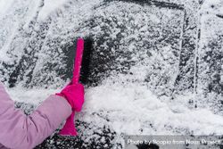 Person brushing off snow from car windshield bDAe80