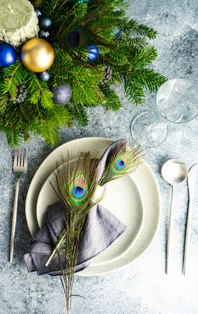 Top view of elegant festive table setting for Christmas dinner with pine branch and peacock feathers