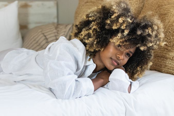Thoughtful Black woman lying on bed in bedroom