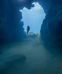 Person in the water diving between rocks