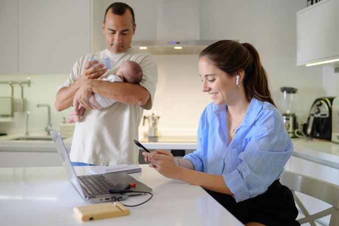 A man and woman holding a baby in front of a laptop