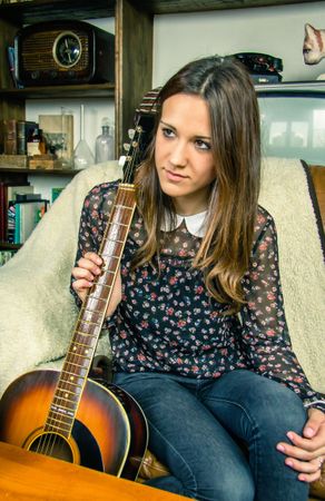 Young hipster woman with acoustic guitar at home
