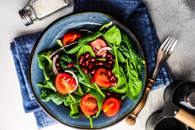 Top view of fresh organic salad with spinach, tomato and pomegranate seeds