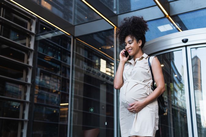 Smiling Black pregnant woman talking on smartphone