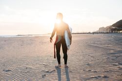 Man walking with surfboard at sunset