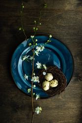 Top view of Easter table setting with blooming tree branch on blue plate
