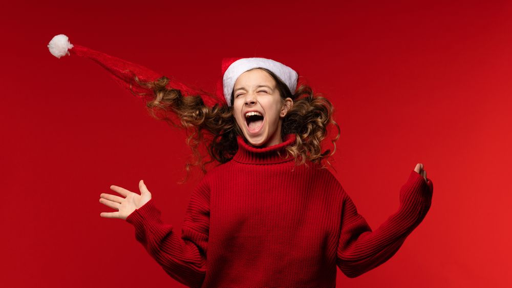 Happy girl in Santa hat joyfully tosses her hair