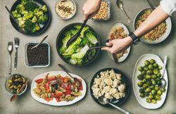 Flat-lay of vegetables, legumes, beans, olives, sprouts, hummus and couscous