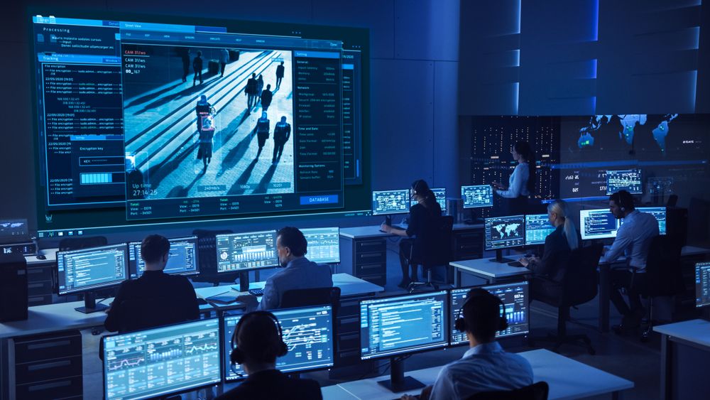 Diverse Team in a High-tech Control Room Monitors Live Surveillance Feeds, Ensuring Security and Data Integrity.