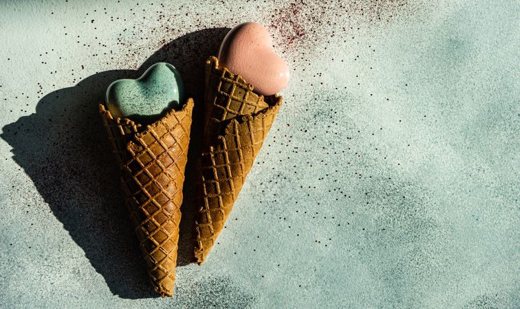 Two ceramic hearts in waffle cones on background with glitter