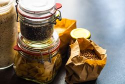 Containers of dried legumes and pasta from pantry with copy space
