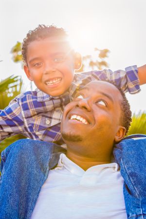 Son and Father Playing Piggyback Outdoors Together.