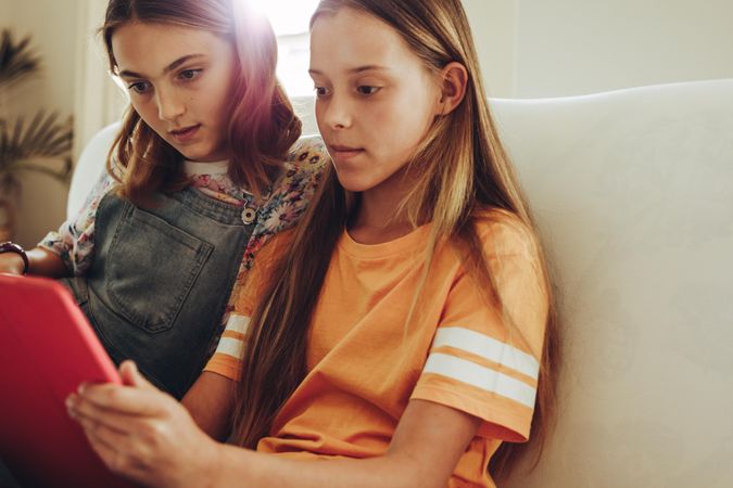 Two girls watching a movie on a tablet pc sitting at home