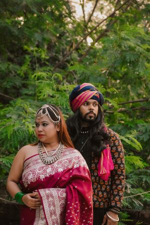 Indian woman in pink saree standing beside a man wearing turban