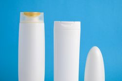 Selection of blank cosmetic bottles in blue room