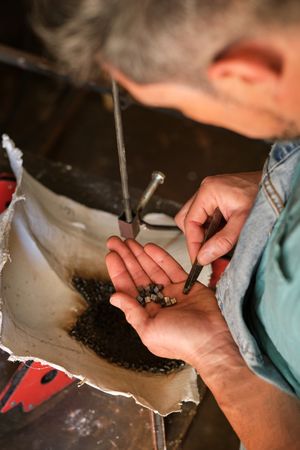 Unrecognizable welder with metal pieces at workbench
