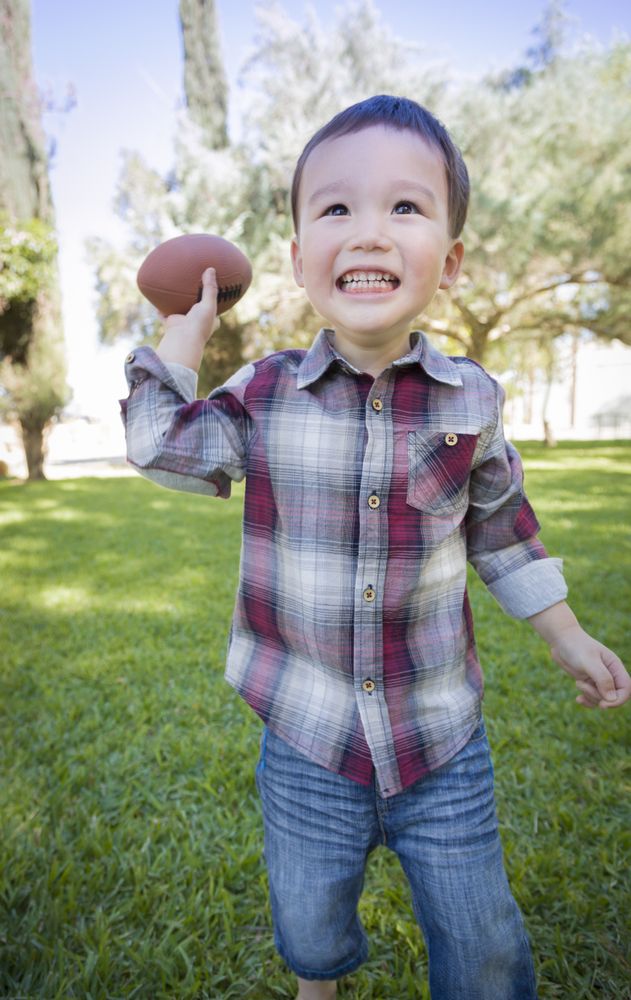Cute Biracial Boy Playing Football Outside