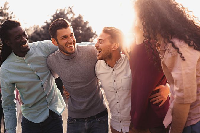 Multi-ethnic group of friends hugging and having fun outdoors