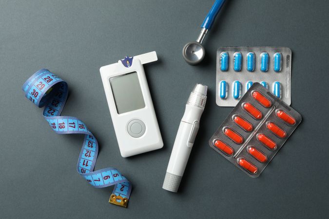 Diabetes accessories on dark background, top view