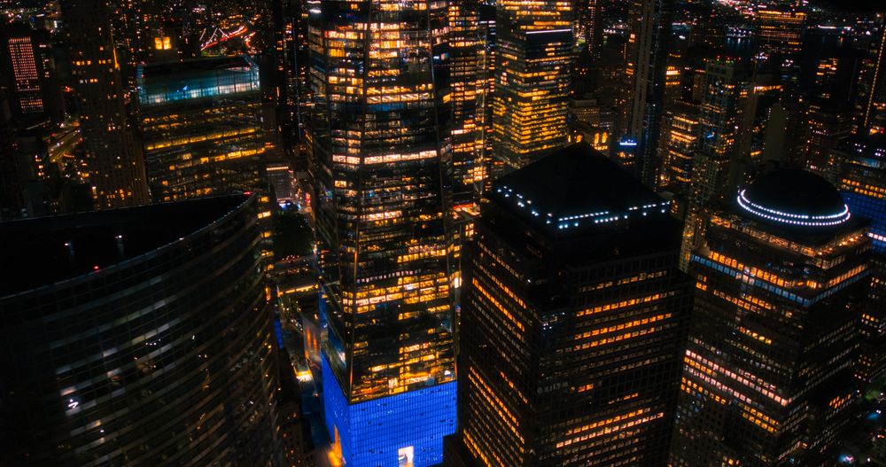 Aerial Night View of New York City Avenues in Manhattan, Business and Residential Building Roofs, Cars and Commercial Vehicles Driving at Night. Helicopter View a Straight Roads with Traffic
