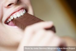 Happy crop anonymous teenage girl taking bite of chocolate bar 47mXok