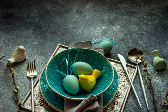Easter holiday table setting with bowl of decorative eggs and bird ornaments