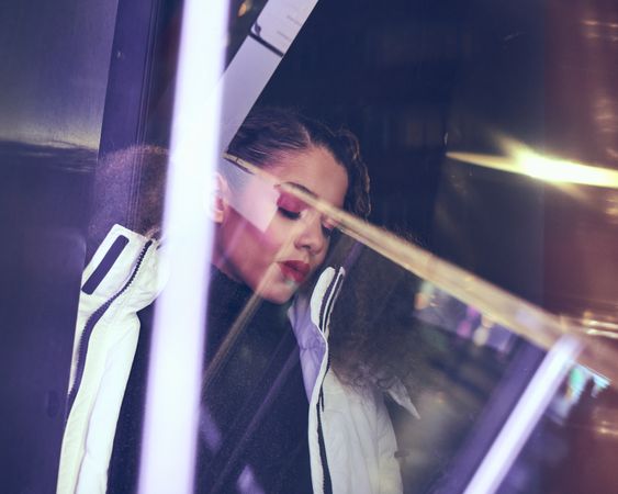 Young woman behind glass and reflections at night