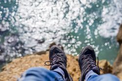 Looking down at boots on cliff with sea below