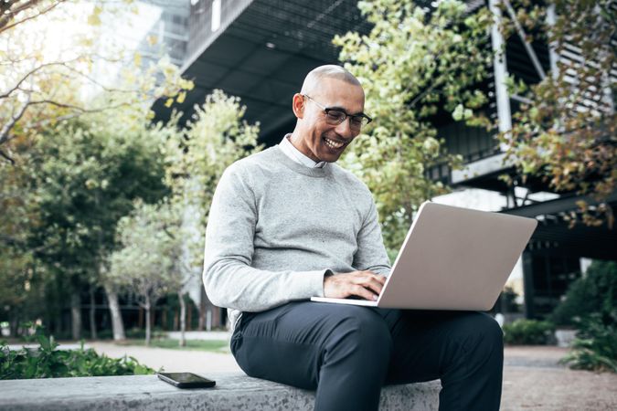 Entrepreneur on laptop sitting outdoors