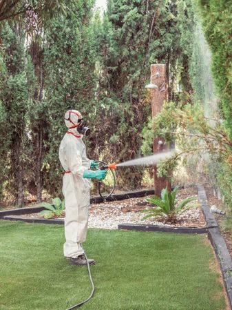 Fumigator in uniform spraying substance on garden