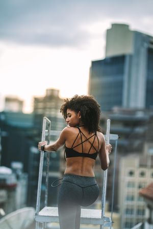 Rear view of a fitness woman climbing rooftop staircase