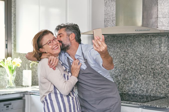 Bearded son kissing aged happy mom on cheek