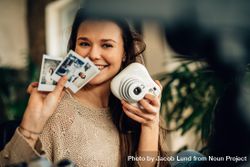 Smiling woman showing an instant camera and photographs taken on it while video recording herself 4MxxE5