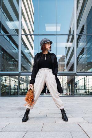 Stylish female holding flowers on street