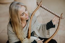 Romantic female musician playing lyre in terrace