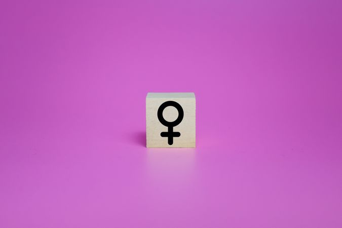 female symbol on wooden blocks isolated on pink background