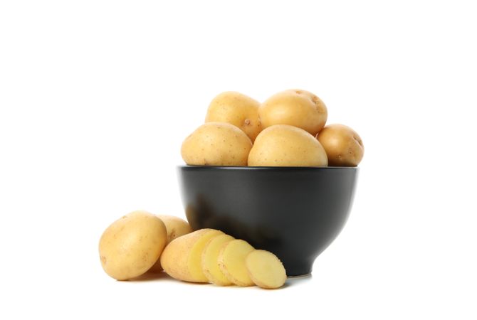 Bowl full of potatoes, with slices on table side view